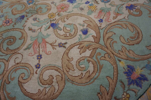 Traditional rug detail showing tan scrolls and colorful flowers against cream and light aqua backgrounds.