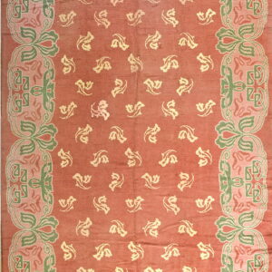 Low pile rug with a rosy-red field, scattered pale yellow motifs, and an elaborate border in sage green and pale pink.