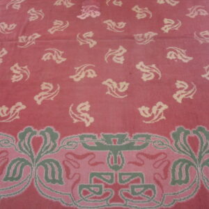 Rose pink rug with scattered cream floral motifs and a detailed border in sage green and lighter pink.