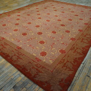 Low-pile rug in dusty rose, red, and gold floral patterns lies on rustic gray and yellow painted wood planks.