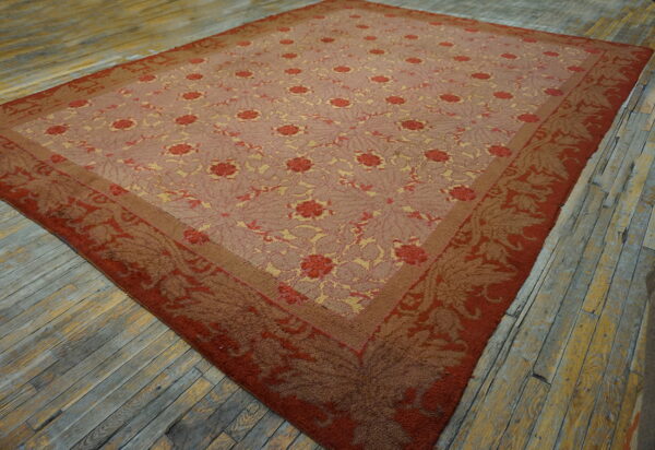 Low-pile rug in dusty rose, red, and gold floral patterns lies on rustic gray and yellow painted wood planks.