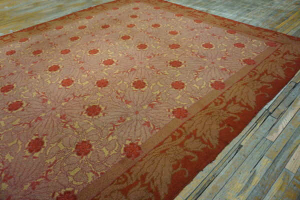 Low-pile rug in rust, gold, and mauve with intricate repeating floral patterns on worn wood floor.
