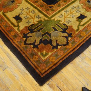 Chunky textured rug in autumnal colors and floral patterns covers worn blonde wood floor.
