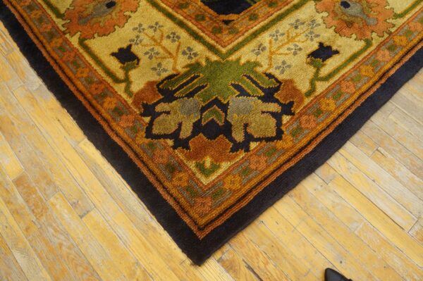 Chunky textured rug in autumnal colors and floral patterns covers worn blonde wood floor.