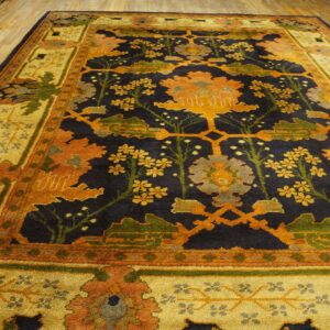 Navy, gold, and orange high-pile rug featuring a dense botanical pattern on light hardwood floors.