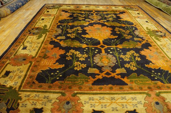 Navy, gold, and orange high-pile rug featuring a dense botanical pattern on light hardwood floors.