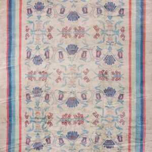 Distressed low pile rug displaying stylized blue, teal, and coral floral motifs on a light beige ground.