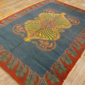 Low-pile blue-green rug features a striking yellow medallion and an orange-red botanical border on wood.