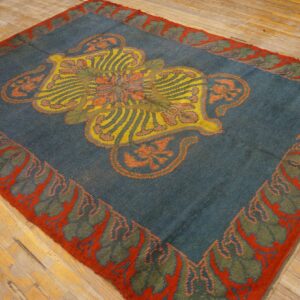 Teal rug with a large yellow, orange, and red stylized medallion and a bold red leaf border on wood floors.