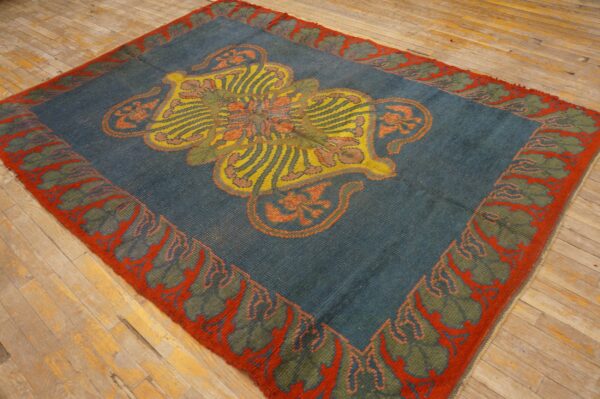 Teal rug with a large yellow, orange, and red stylized medallion and a bold red leaf border on wood floors.