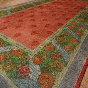 The rust rug field has a dense floral border featuring orange, green, blue, and yellow patterns over distressed wood flooring.