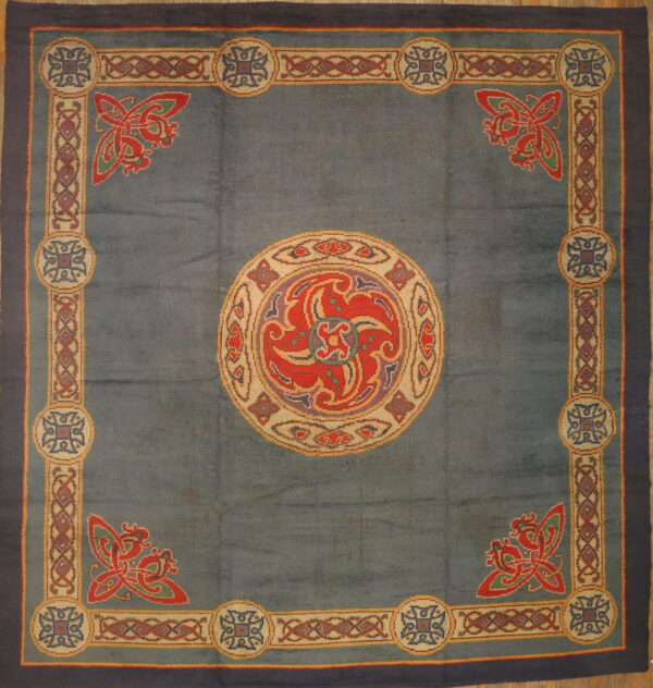 Blue rug with a large red, purple, and cream central medallion and complex multicolored knot border design.