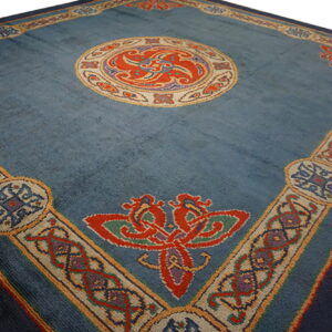 Muted blue rug with a detailed central medallion and wide border featuring red, orange, and purple motifs.