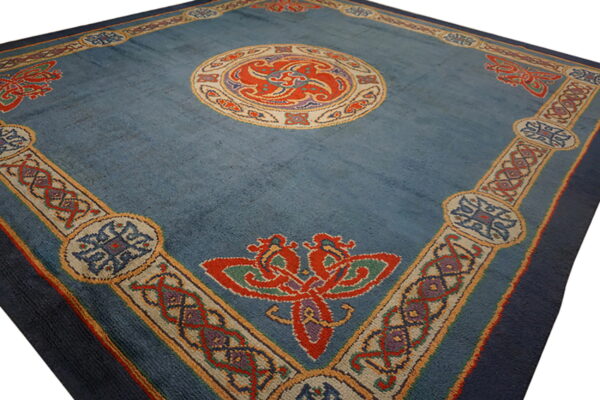 Muted blue rug with a detailed central medallion and wide border featuring red, orange, and purple motifs.