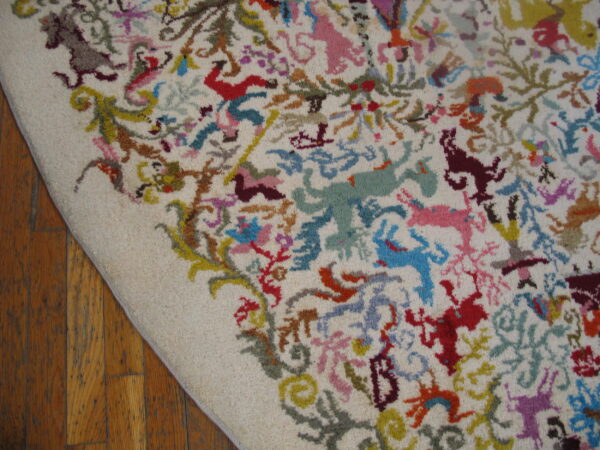 Textured cream rug with a dense pattern of multi-colored abstract figures rests on dark wood plank flooring.