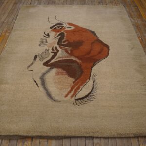 Light beige rug with a large brown and red abstract animal design rests on rustic wood flooring.