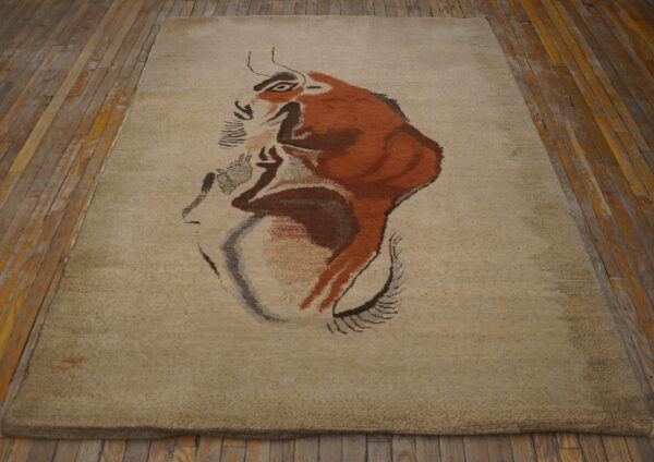 Expressive vintage ecuadorian pictorial art rug from ecuador 2 Light beige rug with a large brown and red abstract animal design rests on rustic wood flooring.
