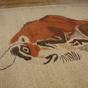 Textured beige rug with an abstract brown and rust-colored animal pattern next to wooden floorboards.