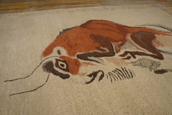 Expressive vintage ecuadorian pictorial art rug from ecuador 4 Textured beige rug with an abstract brown and rust-colored animal pattern next to wooden floorboards.