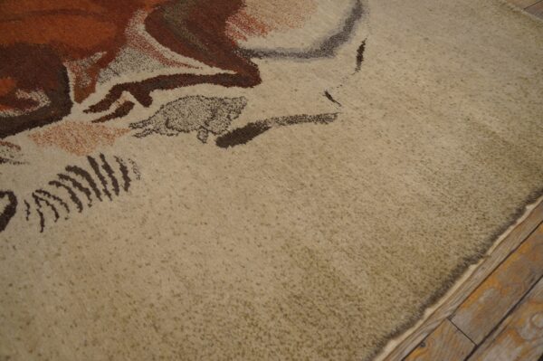 Expressive vintage ecuadorian pictorial art rug from ecuador 5 Close-up of a beige high-pile rug featuring abstract brown and rust colored patterns on rustic wood flooring.