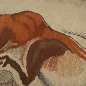 Textured beige rug featuring a prehistoric-style animal design rendered in rusty orange and dark brown.