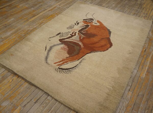Expressive vintage ecuadorian pictorial art rug from ecuador 7 Low-pile beige rug displaying a stylized rust and brown animal portrait on rustic plank wood floors.