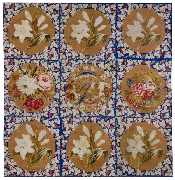 Square rug with nine tan medallions displaying flowers and a central bird on a blue, densely patterned field.