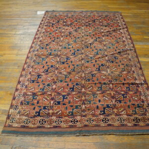 Geometric patterned rug in deep red, blue, and teal colors placed upon distressed wood planks.