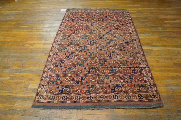 Geometric patterned rug in deep red, blue, and teal colors placed upon distressed wood planks.