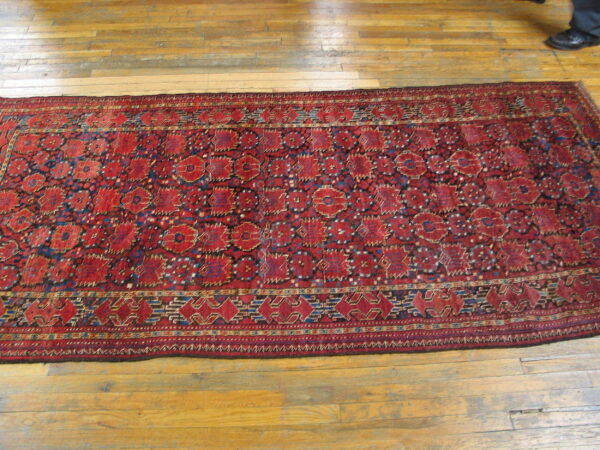 Low-pile red and blue geometric runner rug placed on bright natural hardwood floor planks.
