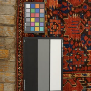 Calibration charts rest on a high-pile rug featuring red, navy, and brown geometric motifs on wood flooring.