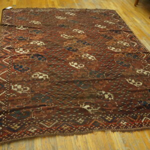 Red and maroon tribal rug featuring blue and cream medallions and geometric borders on hardwood flooring.