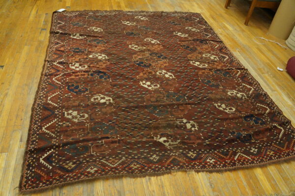 Red and maroon tribal rug featuring blue and cream medallions and geometric borders on hardwood flooring.