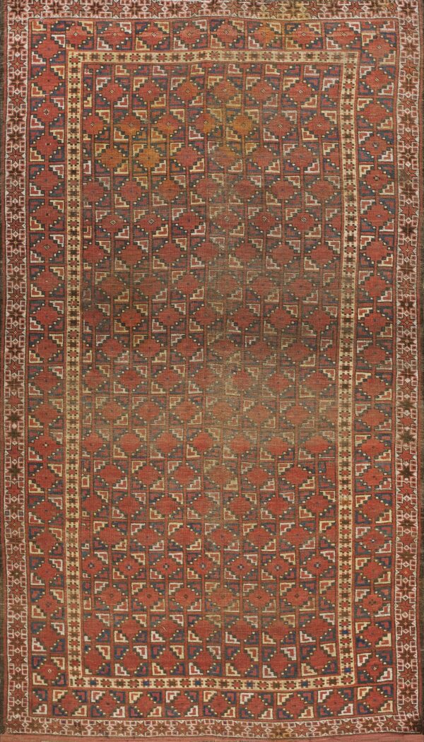 A distressed rust and navy geometric rug with repeating diamonds and complex stepped borders.