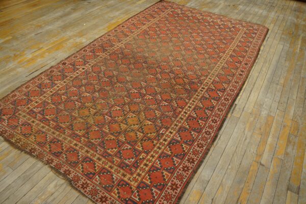 Red, tan, and blue geometric rug rests on wide, rustic wood planks.