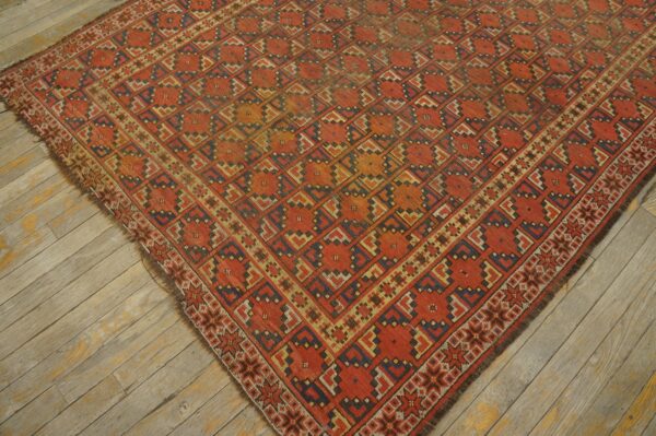 Low-pile rug with a repeating geometric medallion pattern in rust, indigo, and gold on weathered wood planks.