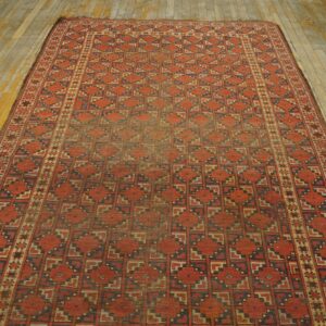 Red and blue patterned low-pile rug displayed on distressed light wood flooring.