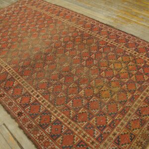 Red and navy geometric area rug with low pile rests on rustic, worn hardwood planks.