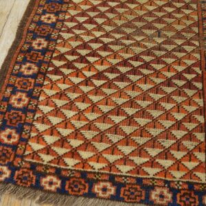 A geometric rug featuring alternating orange, rust, and tan triangles, with a blue border on wood flooring.