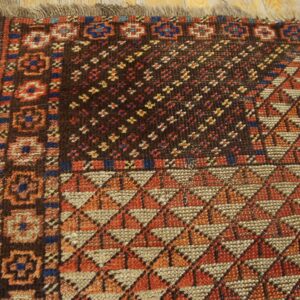 Dark geometric rug showing detailed diamond, star, and border patterns on light brown wood planks.