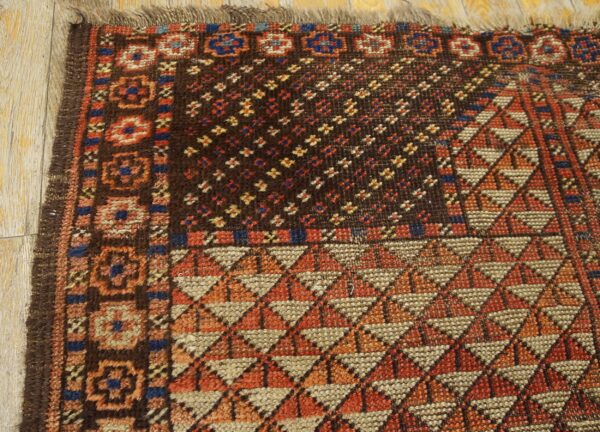 Dark geometric rug showing detailed diamond, star, and border patterns on light brown wood planks.