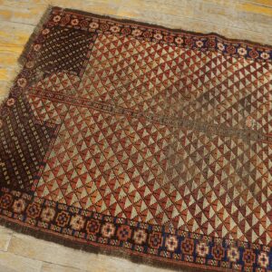 Rust and tan flatweave rug with repeating serrated diamond patterns on rustic wooden floorboards.