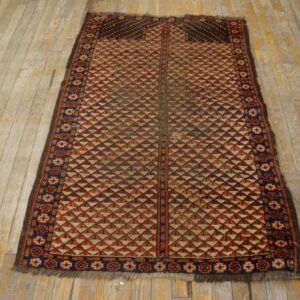 Rust and cream low-pile rug with stacked triangle patterns rests on distressed light wood planks.