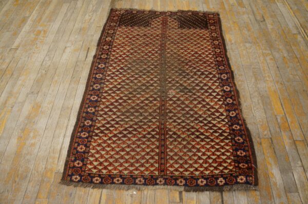 Rust and cream low-pile rug with stacked triangle patterns rests on distressed light wood planks.