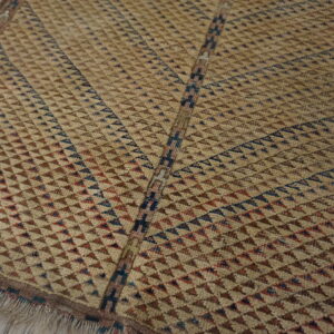 Textured low-pile rug with geometric tan, brown, blue, and red triangles, shown on wood flooring.