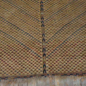 Geometric tan rug detailed with radiating brown, red, and blue triangles on worn wooden planks.