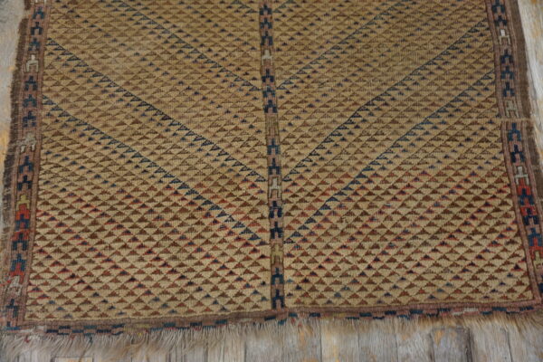 Geometric tan rug detailed with radiating brown, red, and blue triangles on worn wooden planks.