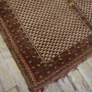 Geometric brown and tan flatweave rug with multicolored borders on distressed gray wooden planks.