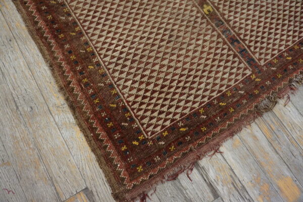 Geometric brown and tan flatweave rug with multicolored borders on distressed gray wooden planks.