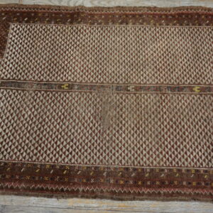 Brown and tan geometric flatweave rug featuring a stepped niche design and dense interlocking triangular motifs on wood flooring.